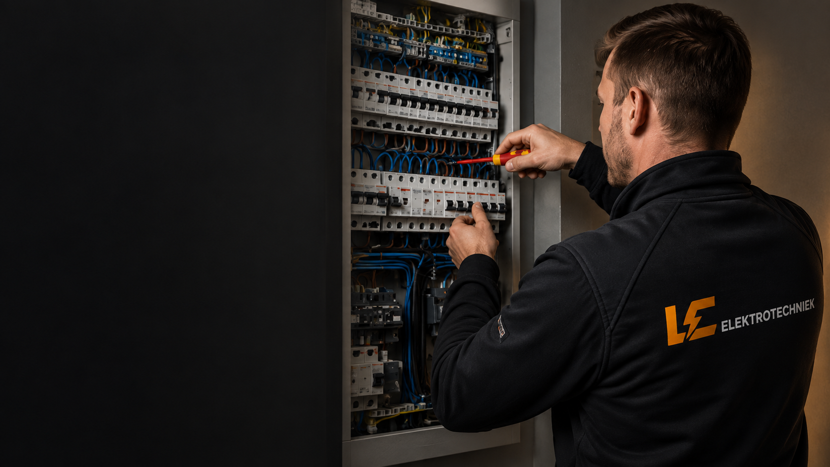 Sfeerbeeld van een elektricien bij een groepenkast, met LC Elektrotechniek op zijn werkvest